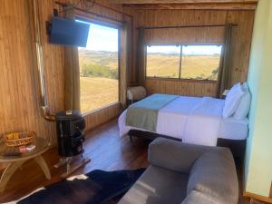 a bedroom with a bed and a couch and a window at Cloud Valley in Bom Jardim da Serra