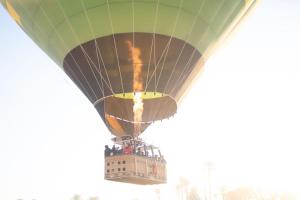 a hot air balloon flying over a building at Luxor hot air balloon co in Jazīrat al ‘Awwāmīyah