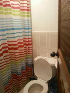 a bathroom with a toilet and a colorful shower curtain at Guesthouse Nelson L in Quito