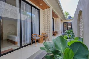 a house with a balcony with a bed and some plants at Rest U Guest House in Nusa Penida