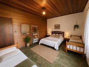 a bedroom with two beds and a tv in it at Sítio pousada recanto curió in Ibiúna
