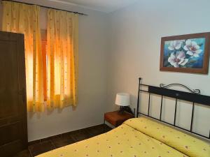 a bedroom with a bed and a window with yellow curtains at Apartamentos Esencia vistas embalse 1 in Hornos