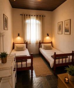 a bedroom with two beds and a window at Sítio pousada recanto curió in Ibiúna