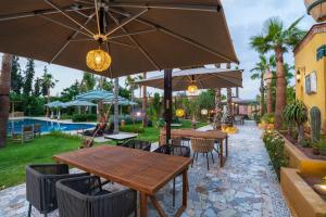 a patio with tables and chairs with umbrellas at Jnane Rihane Marrakech in Marrakesh