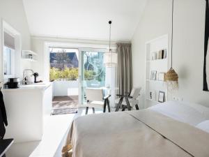 a white bedroom with a white bed and a kitchen at Zilte Suite in Oostkapelle