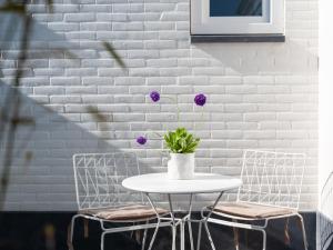 a white table with a vase with purple flowers on it at Zilte Suite in Oostkapelle +9 photos