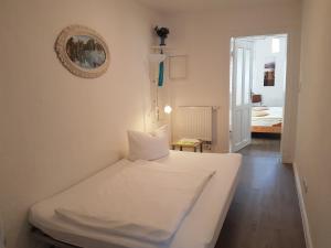 a small bedroom with a white bed and a hallway at Altstadt Fairmietung in Wismar