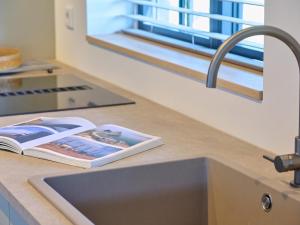 a kitchen counter with a sink and a book on it at Guesthouse het Koetshuis in Bladel +38 photos