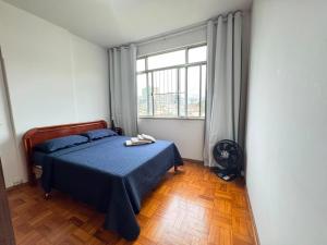 a bedroom with a bed and a large window at Comodidade in Caxambu