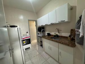 a kitchen with white cabinets and a refrigerator at Comodidade in Caxambu