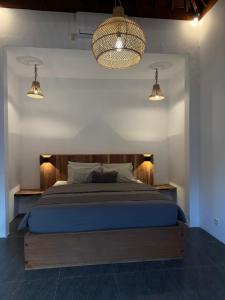 a bedroom with a bed with blue sheets and two lights at SinCity Nature Private Pool Villa in Tanjung