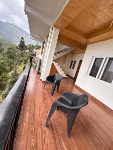 a house with black chairs on a balcony at Forest Breeze Homestay in Kanatal