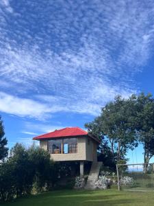 a small house with a red roof on a field at Refugio del venado Cuicocha in Cotacachi