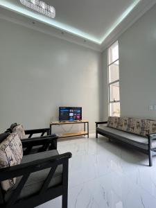 a living room with couches and a flat screen tv at Xodó de Casa, Paracuru in Paracuru