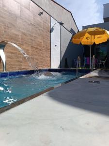 a swimming pool with an umbrella and water at Xodó de Casa, Paracuru in Paracuru