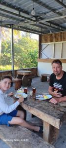 two men sitting at a wooden table with plates of food at 3Z Homestay in Bayan