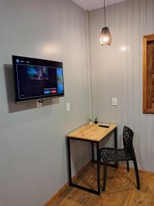 a room with a table and a chair and a tv on the wall at Casa VNE 01 in Araranguá