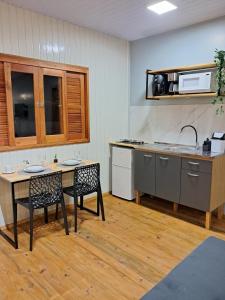 a kitchen with a table and two chairs and a sink at Casa VNE 01 in Araranguá