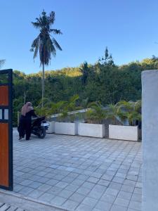 a person sitting on a motorcycle in a parking lot at RUMAH BAIQ Villa in Kuta Lombok +3 photos