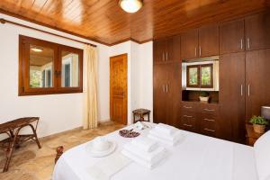 a room with a bed with white sheets and wooden cabinets at Villa Old Vineyard in Kontogiannátika +45 photos
