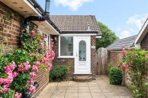 a brick house with a white door and pink flowers at Downs Escape By My Getaways in Lancing