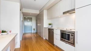 a kitchen with white walls and wooden floors at Resort & Spa 6316 withTropical Pool Views - 230m to Beach in Kingscliff +11 photos