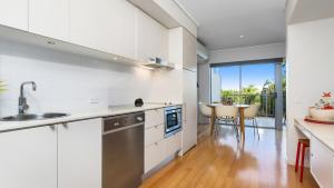 a kitchen with white cabinets and a table with chairs at Resort & Spa 6316 withTropical Pool Views - 230m to Beach in Kingscliff
