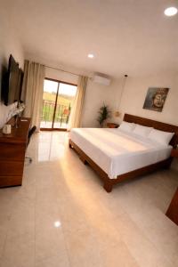 a bedroom with a large bed and a television at Hotel Casa del Rio in Santiago Tuxtla