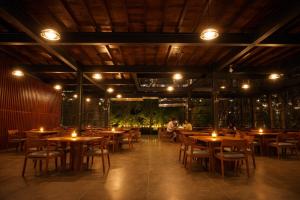 a restaurant with wooden tables and chairs and lights at Camp Thuduwa Udawalawe in Udawalawe