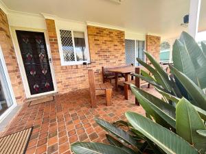 a patio with tables and chairs and a brick wall at Mountain View Hat Head - Bring your own linen. in Hat Head