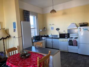a small kitchen with a table and a refrigerator at Sullivans backpackers in Waimate