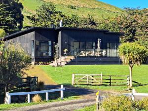 a black house with a fence in front of it at Christchurch - Port Levy, Bed & Breakfast in Port Levy +24 photos