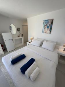 a white bed with two blue pillows on it at Rineia Complex by Live&Travel in Mikonos