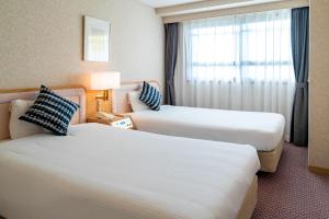 a hotel room with two beds and a window at Seagaia Forest Condominiums in Miyazaki