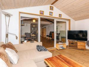 a living room with a couch and a flat screen tv at Charming cottage near forest in Farsø in Farsø
