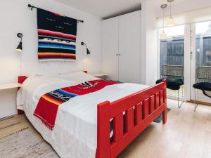 a red bed in a white bedroom with a red headboard at sunny Cottage with Spa facility in Gedser