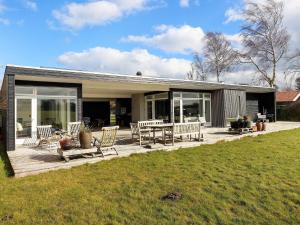 a house with a deck with chairs and a table at sunny Cottage with Spa facility in Gedser