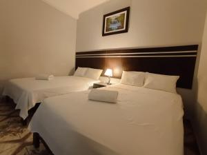 two beds in a hotel room with white sheets at Hotel Valle Verde in Tarapoto