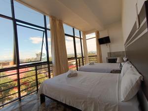 a bedroom with two beds and a large window at Hotel Valle Verde in Tarapoto