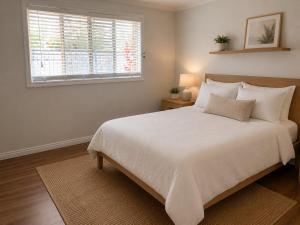a bedroom with a large white bed with a window at Charming & Spacious 5 Bedroom Bayside House with Pool in Birkdale