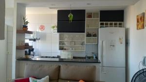 a kitchen with a couch and a white refrigerator at Flat Aconchego Olinda - Vista e Piscina in Olinda