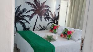 a white bed with a green blanket and palm trees on it at Flat Aconchego Olinda - Vista e Piscina in Olinda +15 photos
