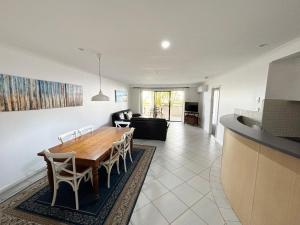 a kitchen and living room with a wooden table and chairs at Jubilee Apartment 03 - Bring your own linen in South West Rocks