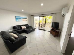 a living room with a couch and a television at Jubilee Apartment 03 - Bring your own linen in South West Rocks