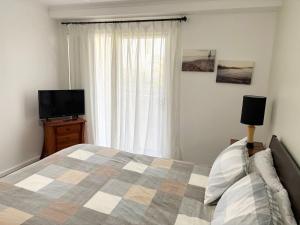 a bedroom with a bed and a flat screen tv at Jubilee Apartment 03 - Bring your own linen in South West Rocks +9 photos