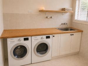a kitchen with two washing machines and a sink at Charming & Spacious 5 Bedroom Bayside House with Pool in Birkdale