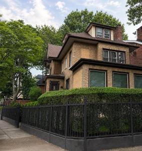 a brick house with a fence in front of it at Luxury Pre-War Townhouse Bronx 5BR in University Heights