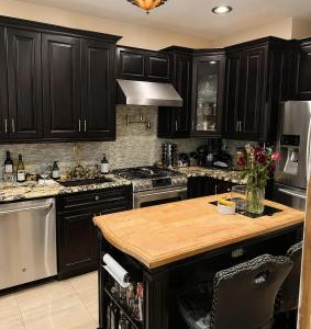 a kitchen with black cabinets and a wooden counter top at Luxury Pre-War Townhouse Bronx 5BR in University Heights