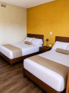 Zwei Betten in einem Hotelzimmer mit gelben Wänden in der Unterkunft Hotel Barrio Boutique in Monterrey