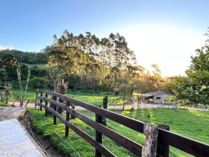 a wooden fence with a giraffe in a field at Chalé Luar da Serra in Camanducaia